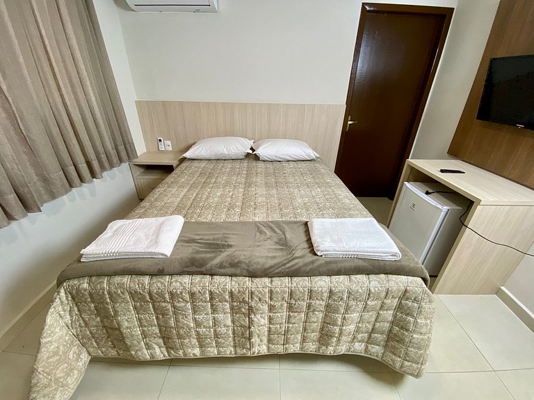 Quarto casal confortável com TV e frigobar